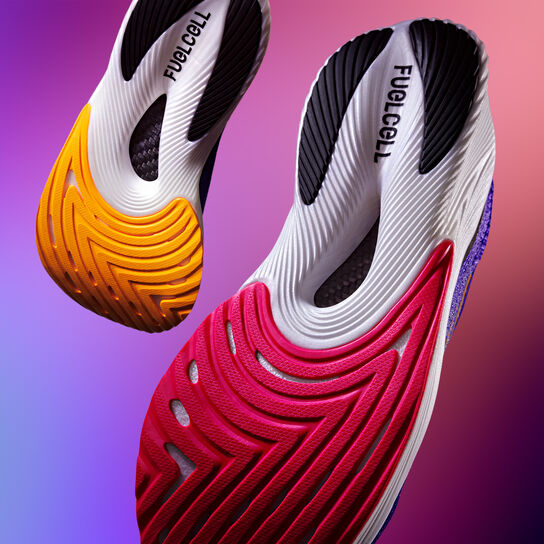 Two floating shoes, showing the bottom sole of the FuelCell RC Elite shoe on a gradient background 