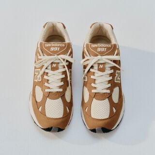 A pair of New Balance Made in UK sneakers sitting in a white studio environment. 