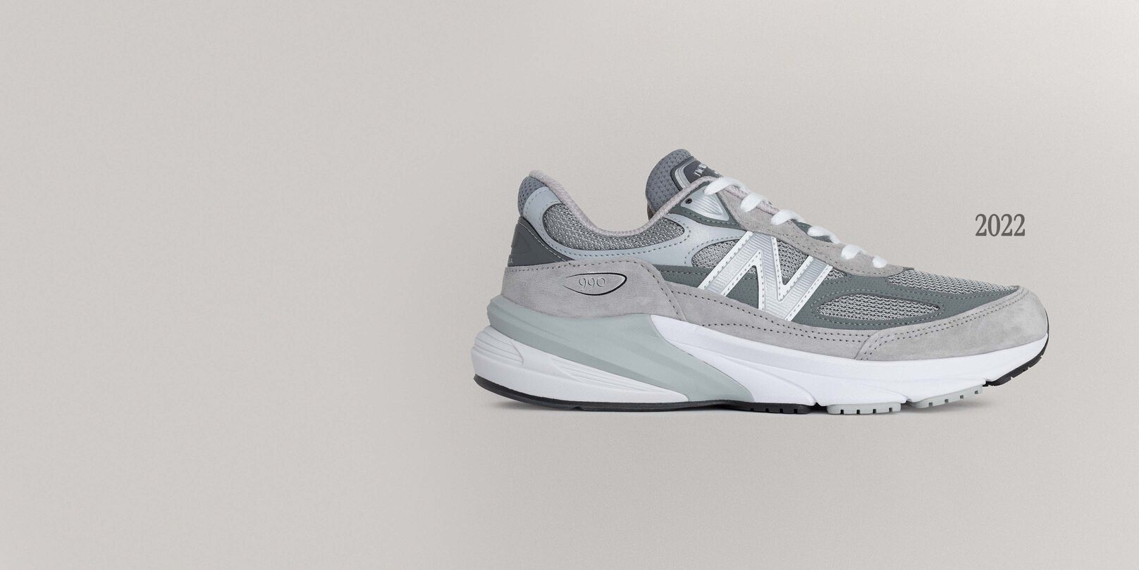 A grey 990v6 sneaker sitting on a grey background.