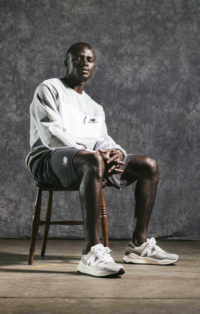 Sadio Mané sitting on chair in studio wearing grey NB apparel and shoes. 