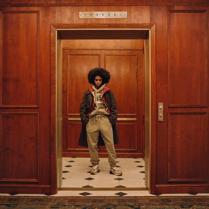 A woman standing in an elevator wearing New Balance Made in USA apparel and footwear.