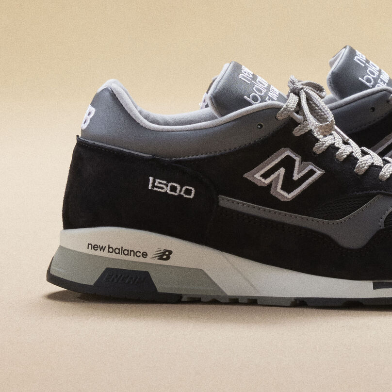 Close up of one pair of black New Balance Made in UK sneakers sitting in a beige studio environment.