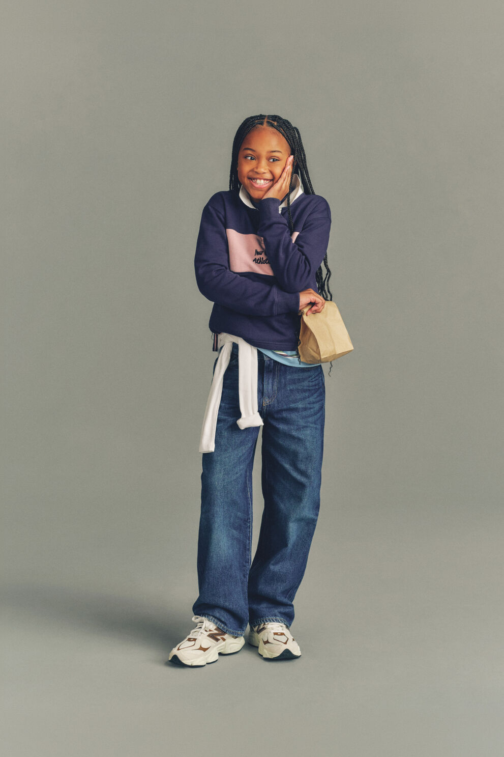 Young kid standing in front of a bike wearing blue jeans and a pink shirt. 